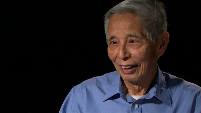 Professor Tunney Lee seated in front of a black background for an on camera interview.