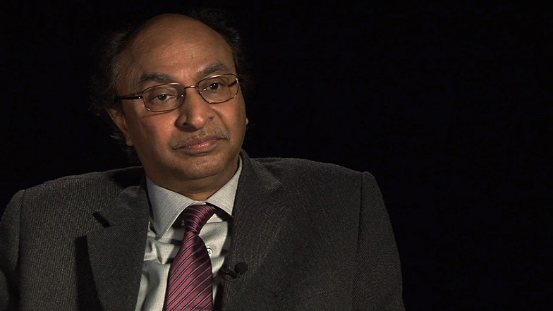 Bishwapriya Sanyal seated in front of a black background for an on camera interview.