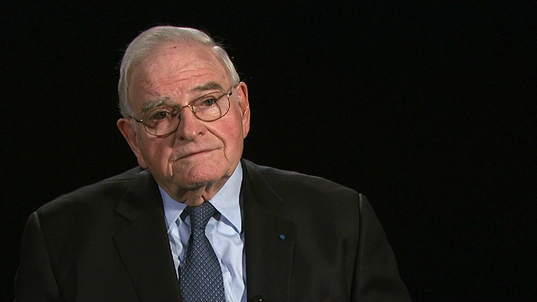 Paul E. Gray seated in front of a black background for an on camera interview.