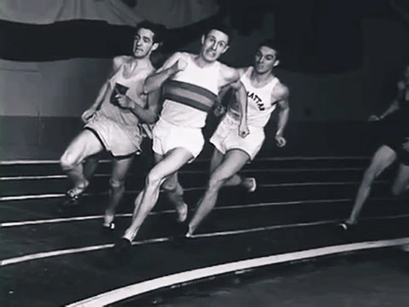Three men sprinting on a track, photo taken by stroboscope makes them appear frozen mid-stride.