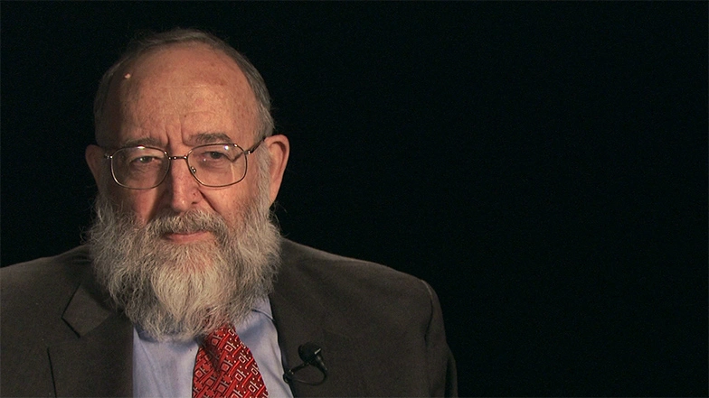 Joel Moses seated in front of a black background for an on camera interview.