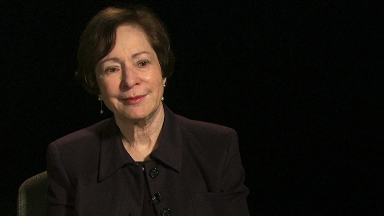 Suzanne Berger is seated in front of a black background for an on camera interview, smiling