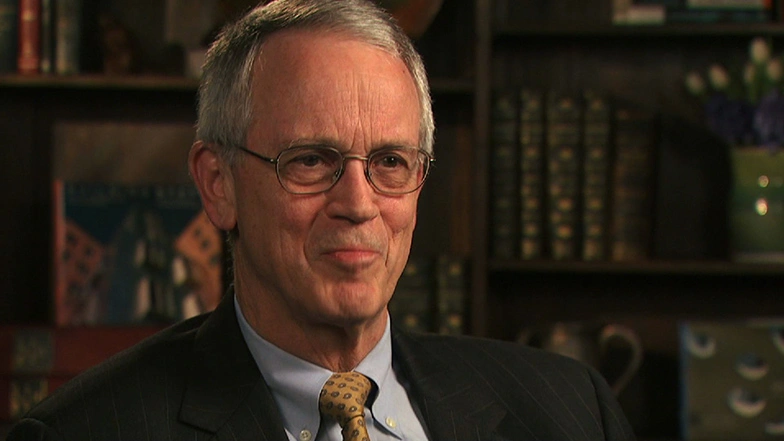Charles Vest sitting in front of bookcase for on camera interview, looking ahead