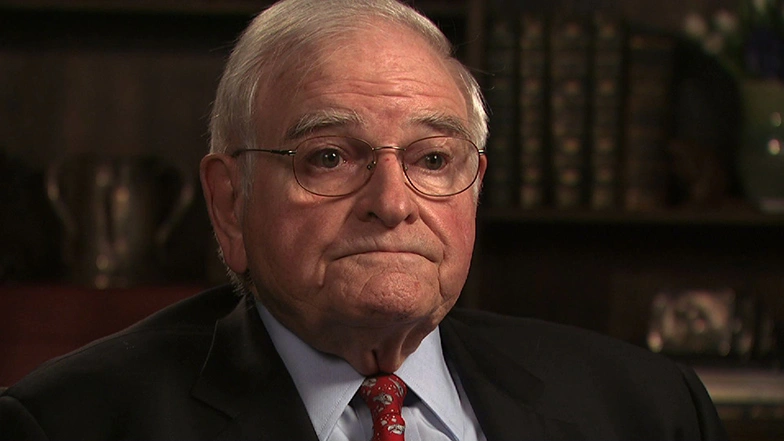 Paul E. Gray seated in front of a black background for an on camera interview.