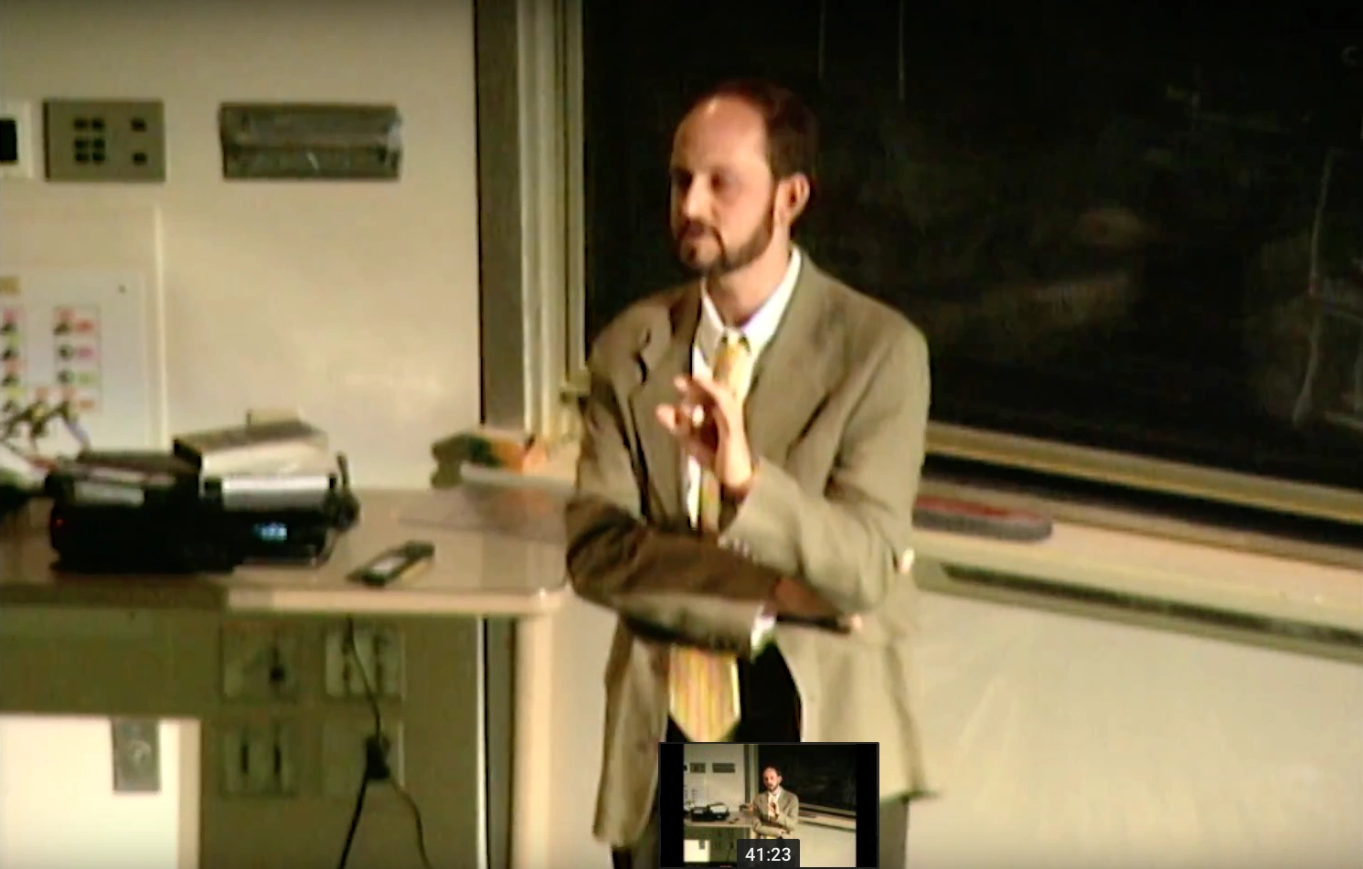 Marc Hauser speaking in a classroom, standing in front of a chalkboard
