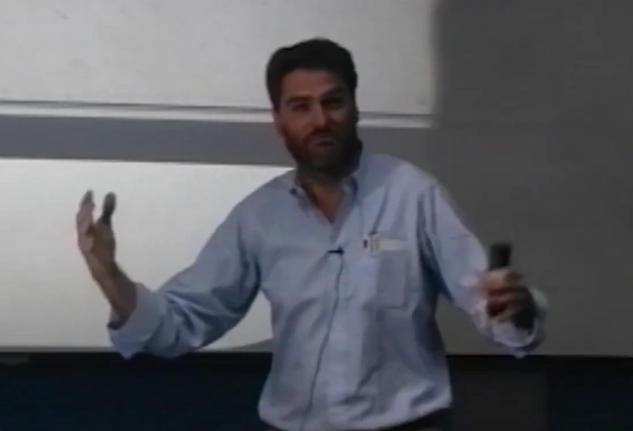 Chris McKay gives impassioned lecture in front of a projector screen