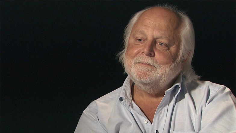 A. Neil Pappalard seated in front of a black background for an on camera interview.