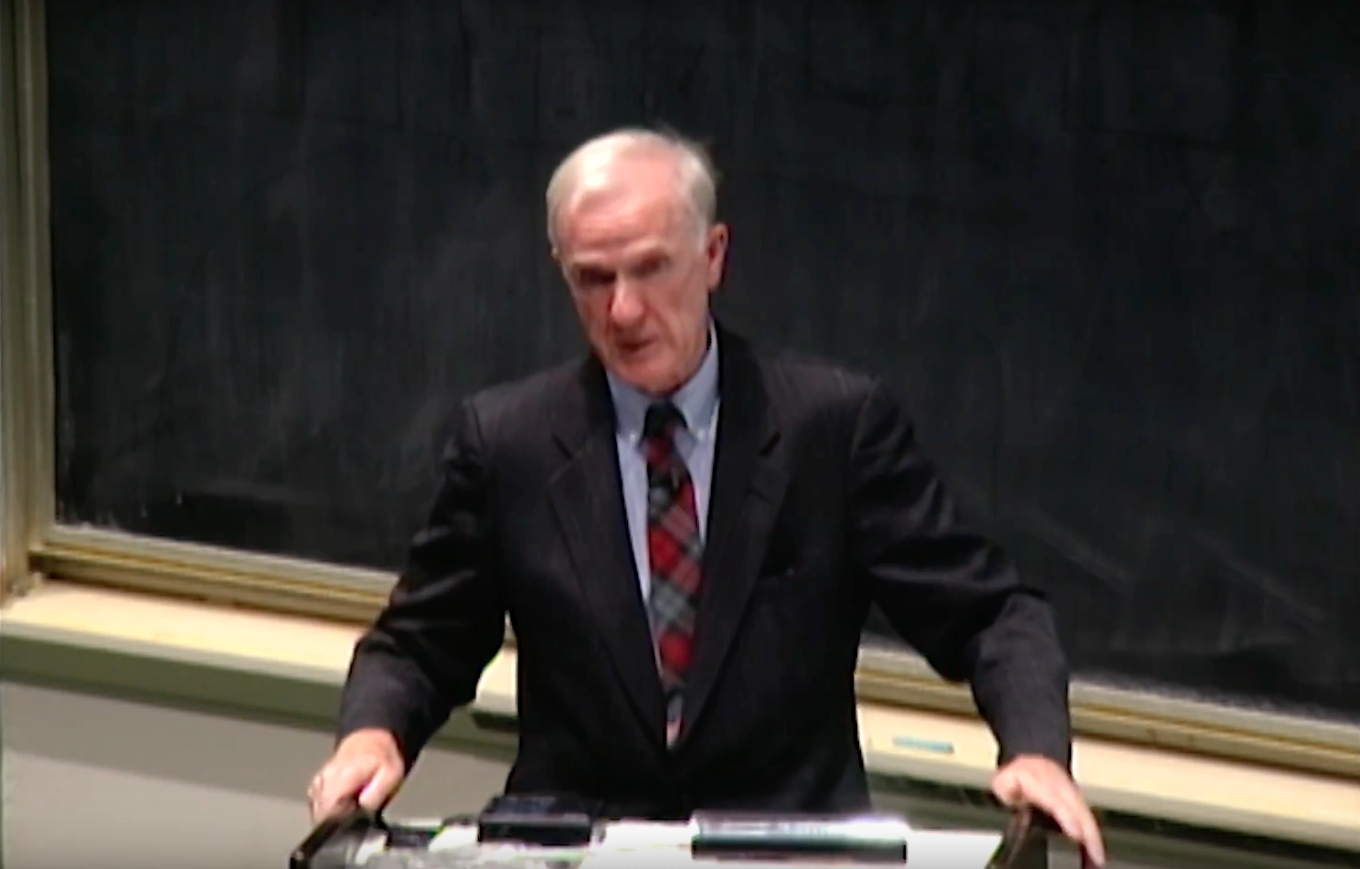 Paul Penfield speaking at podium in classroom, chalkboard in the background.