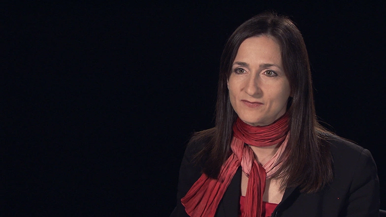 Sara Seager seated in front of a black background for an on camera interview.