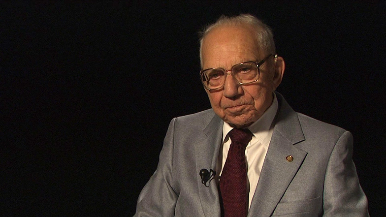 Leo L. Beranek seated in front of a black background for an on camera interview.