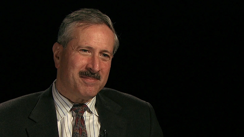 Steve Lerman seated in front of a black background for an on camera interview.