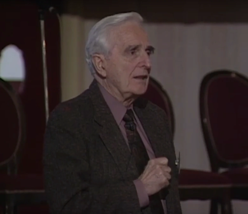 Doug Engelbart standing in a conference room, looking ahead.