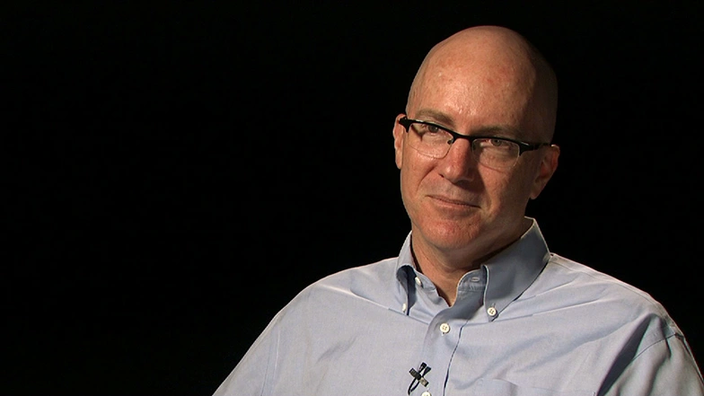 Charles Stewart seated in front of a black background for an on camera interview.